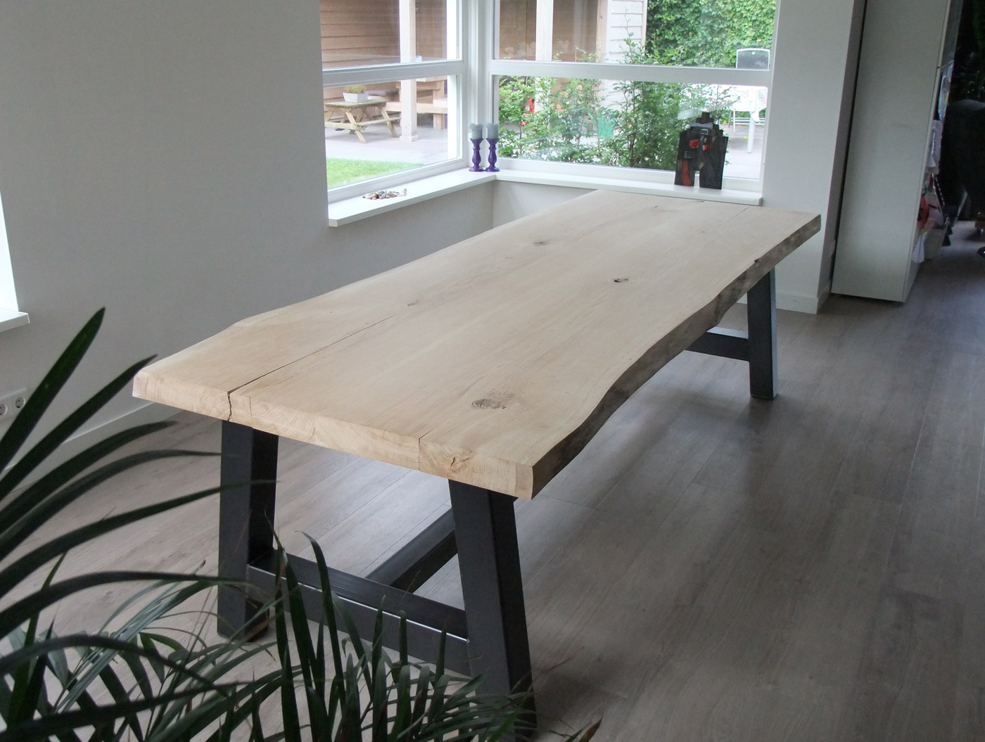 Massief eiken tafel met boomstamblad en stalen onderstel